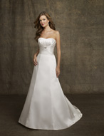 Bridal Dress: AngelinaFaccenda - 1051 - Silk Satin  Dipped strapless bodice with a spray of contoured pleats extending from the peaked empire. Crystal beaded brooch meets the princess line gown with chapel length train. Colors: Light Ivory 