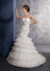 Bridal Dress: Mori Lee Voyage Collection: 6603 - Ruffled Organza  Asymmetrical draping shaping the surplus, starpless fitted torso. Tiers of pleated organza shape the skirt on this mermaid gown with a corset tie back and sweep train. Available in three lengths: 55
