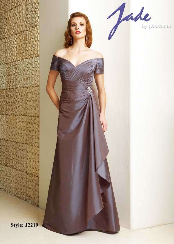 Prom Dress: JADE - J2219  Catalogue Color:  VICTORIAN (VT)  Silhouette:  Jade Taffeta gown with off the shoulder short sleeves. Criss cross shirred bodice and drop waist with side beaded applique. Back of gown has gathers. A-line skirt has side ruffle overlay.   Fabric-top layer:  JADE TAFFETA  Accessory:  N/A  Skirt Length:  Floor  Size Range:   2-26  